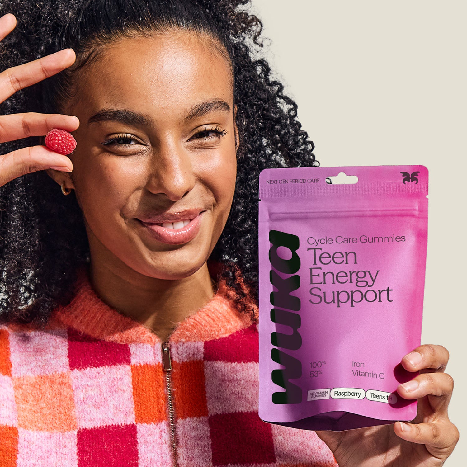 Smiling teen girl holding WUKA Teen Iron Support Gummies in raspberry flavour – vegan vitamin supplement to boost energy and reduce fatigue.