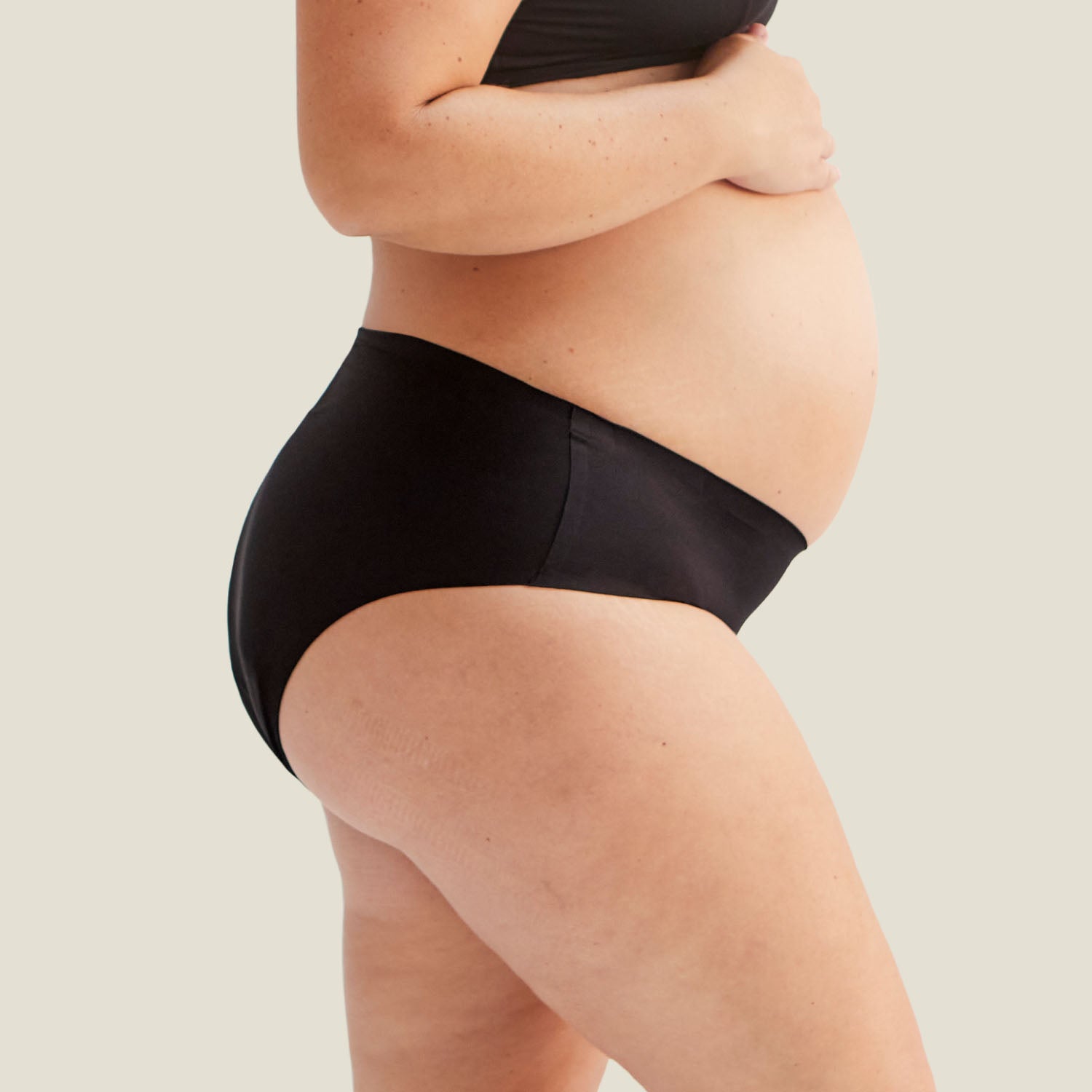 Side profile of pregnant model wearing WUKA Stretch™ Postpartum Period Pants, offering gentle support and leak-proof protection.